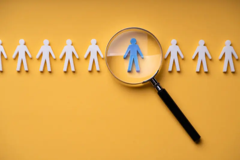 Illustration of a magnifying lens scanning multiple candidates – symbolizing talent screening