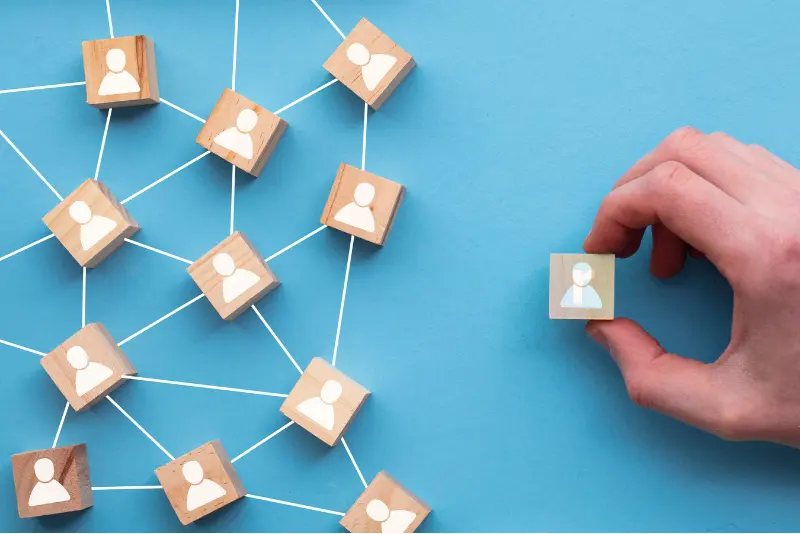 Hand placing an employee figure into a team – symbolizing perfect lateral fit in hiring